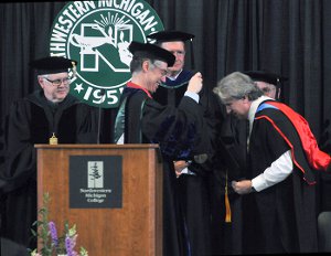 NMC Vice President Stephen Siciliano gives a faculty excellence award to astronomy instructor Jerry Dobek at NMC's 2015 Commencement.
