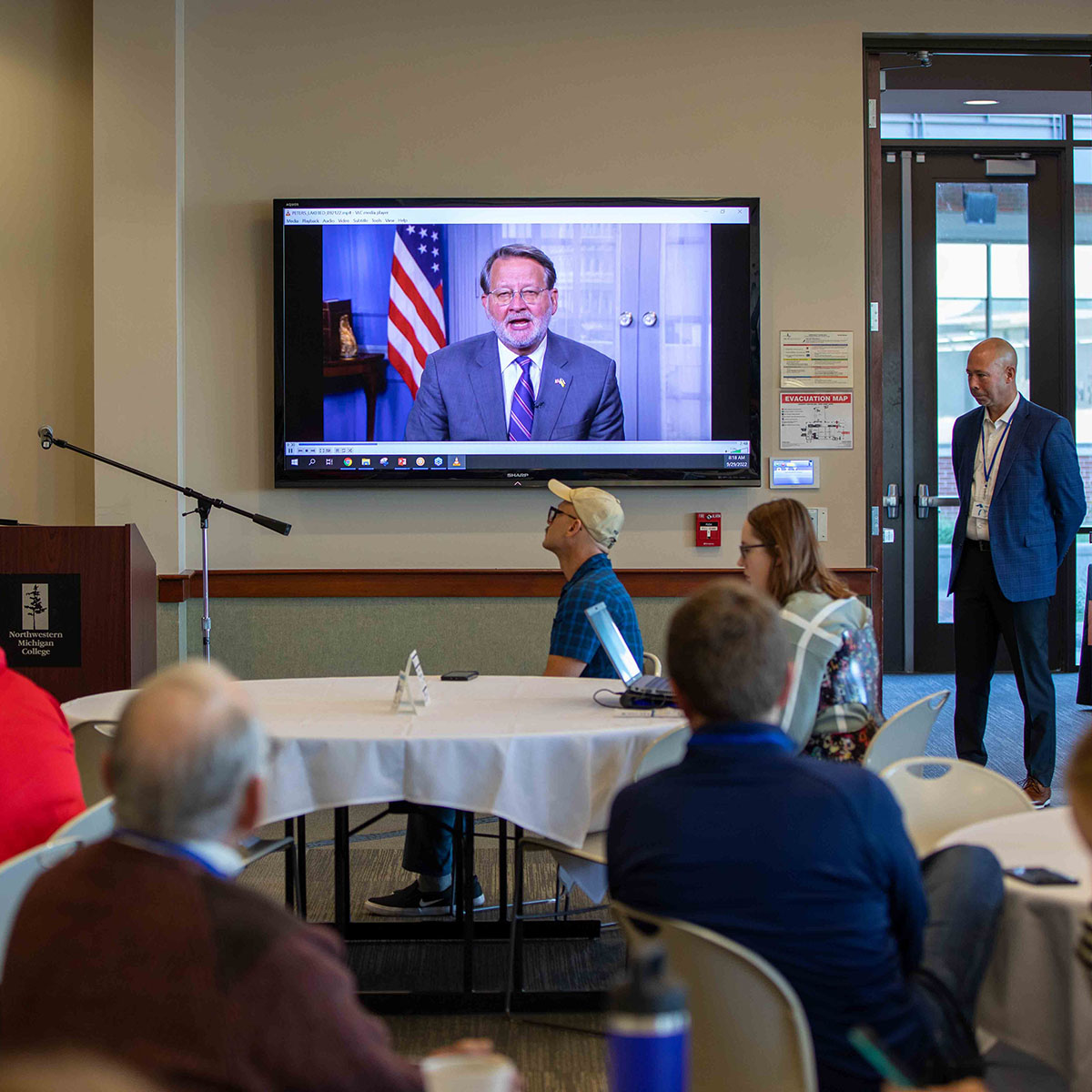 U.S. Senator Gary Peters, D-Mich., speaks via video at a Lakebed 2030 event in 2022 while Hans VanSumeren, Senior Director of the Ocean Enterprise Initiative and Marine Technology Society and the founding director of NMC's Great Lakes Water Studies Institute, looks on.