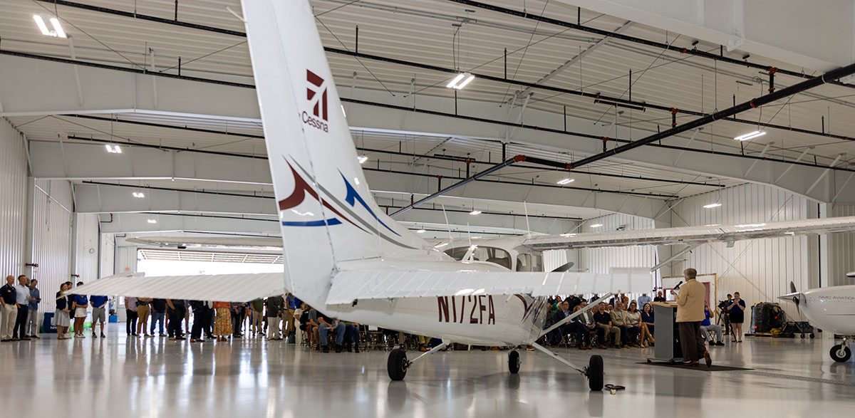 A scene from the September 15 groundbreaking for NMC's expanded aviation hangar, with a plan and a crowd behind it
