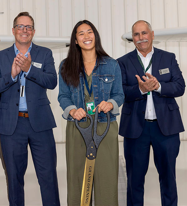 NMC aviation student Meigan Lanning cuts the ribbon at the hangar groundbreaking while program director Alex Bloye and chief flight instructor Frank Jabour look on.