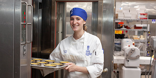 Great Lakes Culinary Institute baking certificate program student Caroline Clark pulls pastry shells from a commercial oven